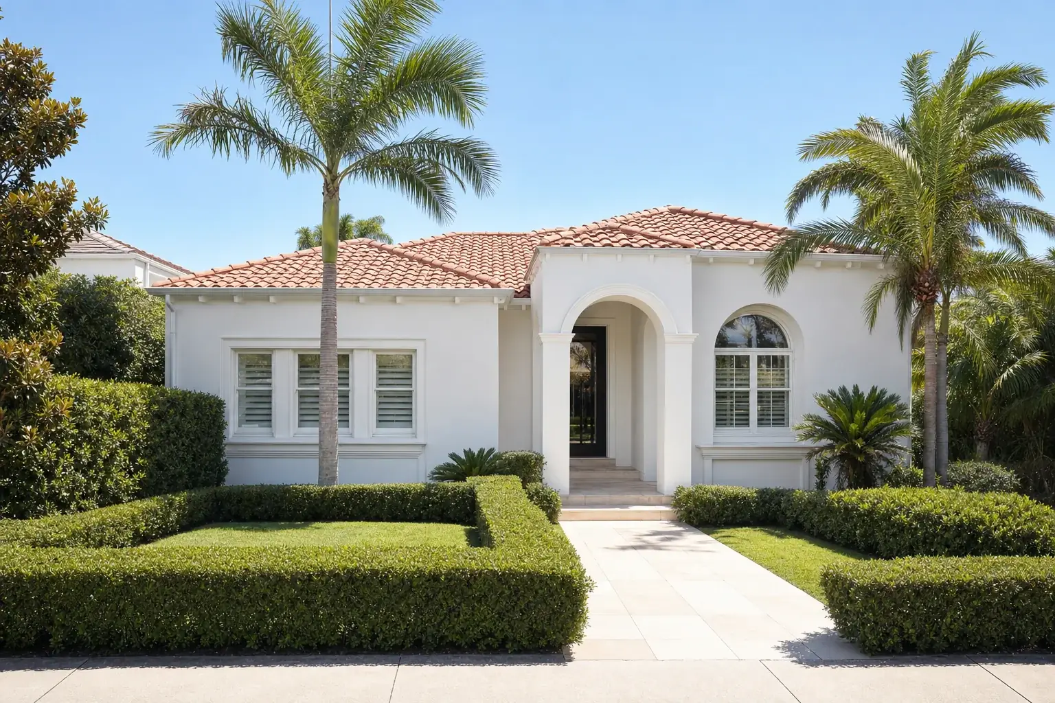 An Australian villa style home, single storey and rendered white with an arched entry portico