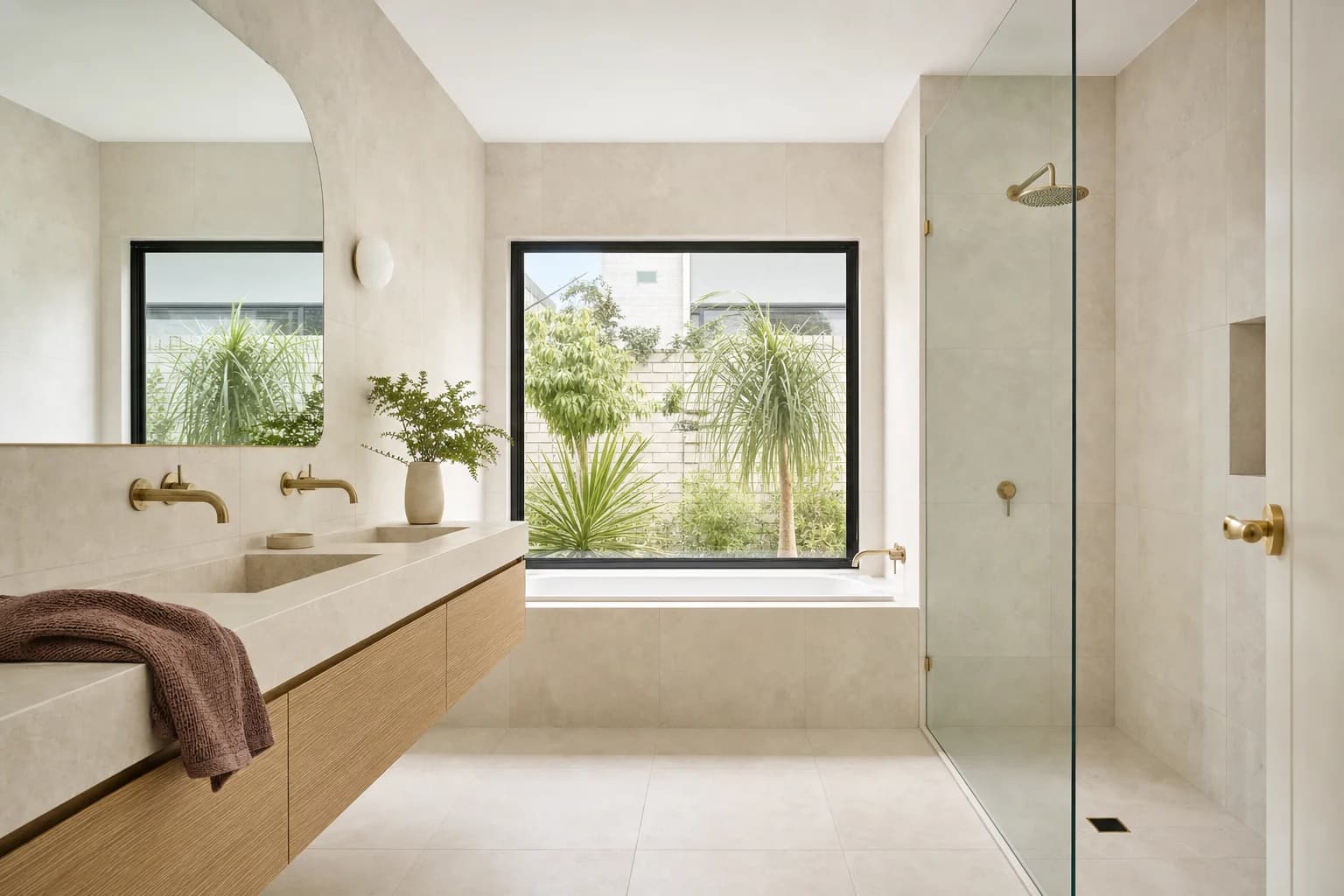 A renovated family bathroom with a separate built-in bath and a glass shower screen, pale limestone tiling and a wide oak vanity
