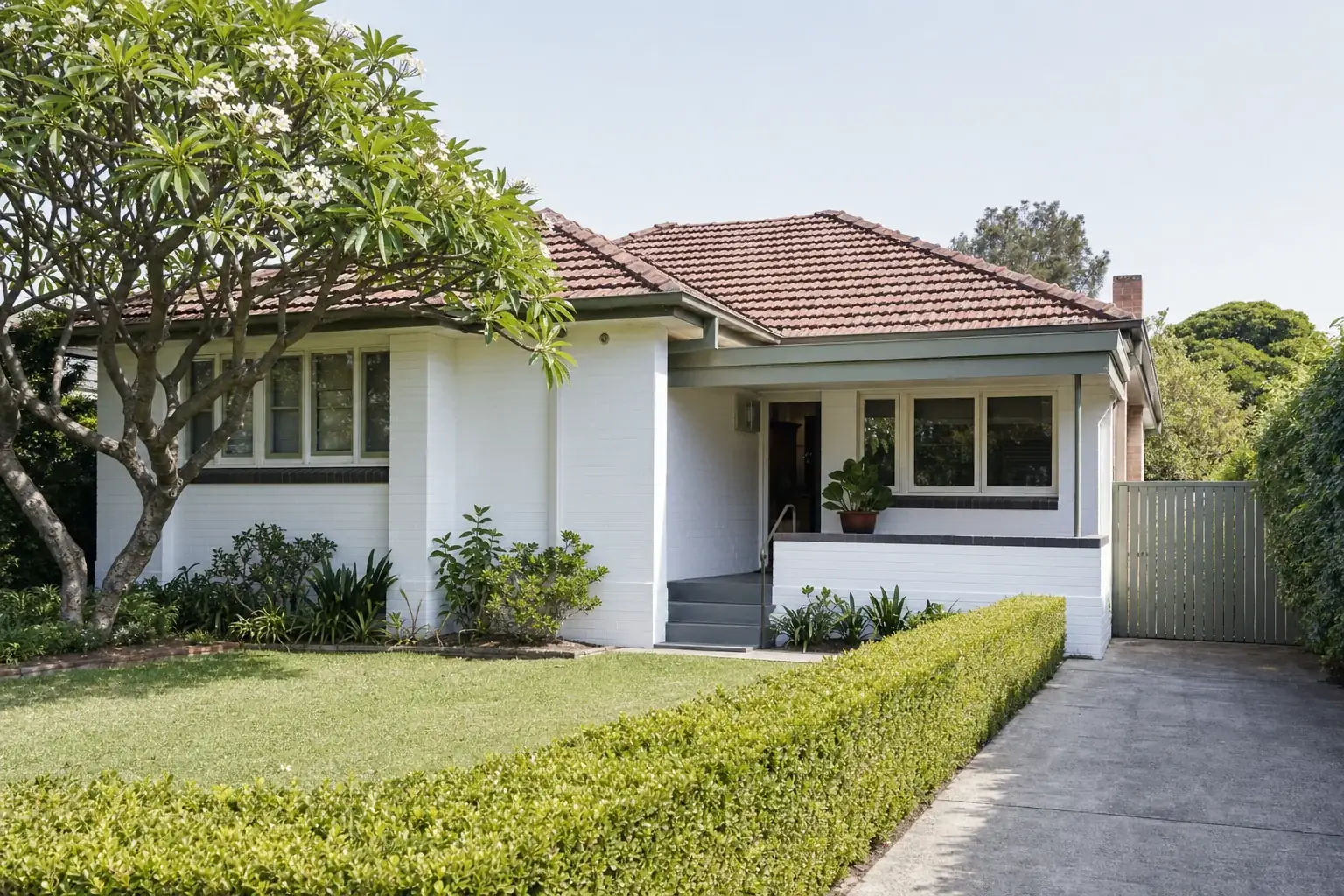 A post-war Australian single storey house in painted brick with a tiled hip roof and a small front porch
