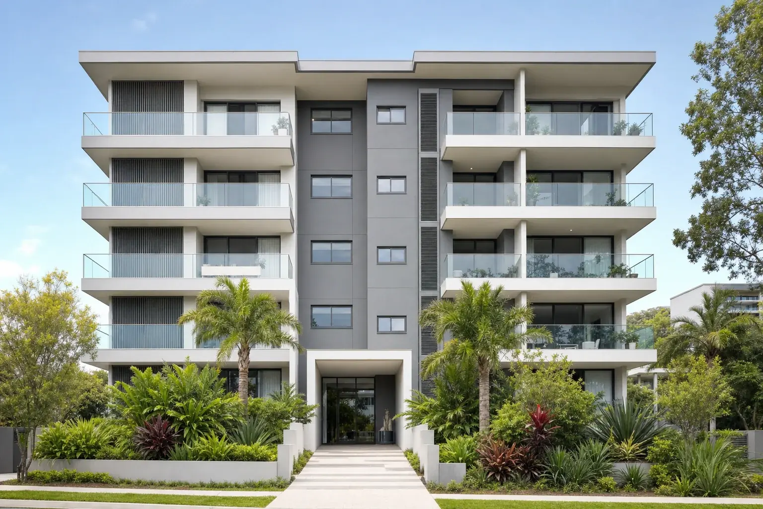 A modern Australian low rise apartment building with glass balustrades and landscaped garden beds at the entry