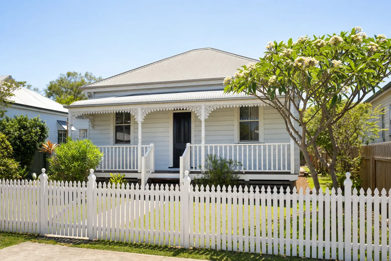 An older Australian timber cottage with painted weatherboard, a small front verandah and a tin roof